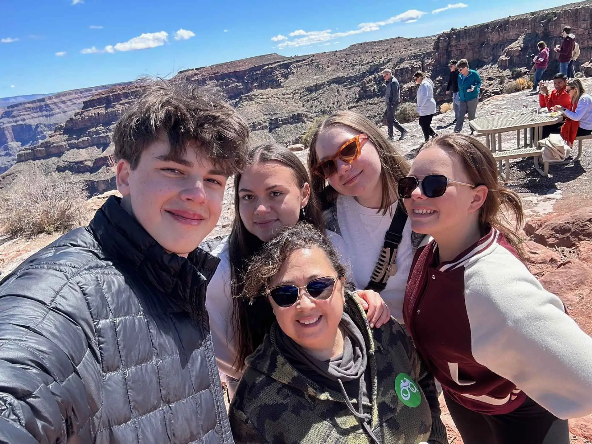 International participants and host family members take a group selfie at a scenic U.S. destination during a cross-cultural homestay experience.