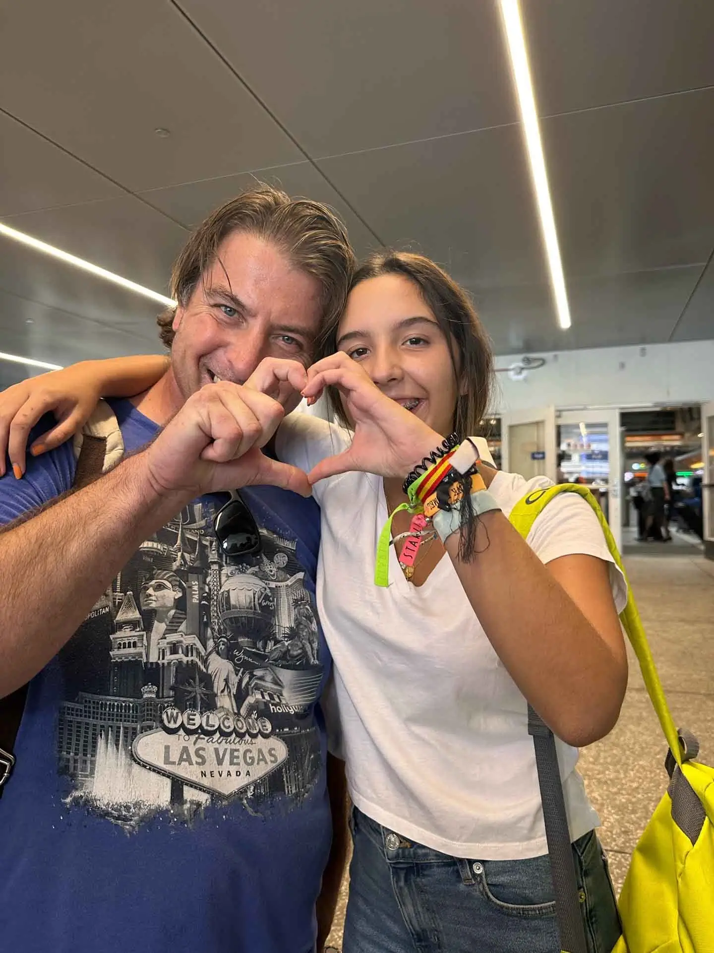 An American host parent and international participant smile and form a heart shape with their hands during a meaningful cultural exchange moment.